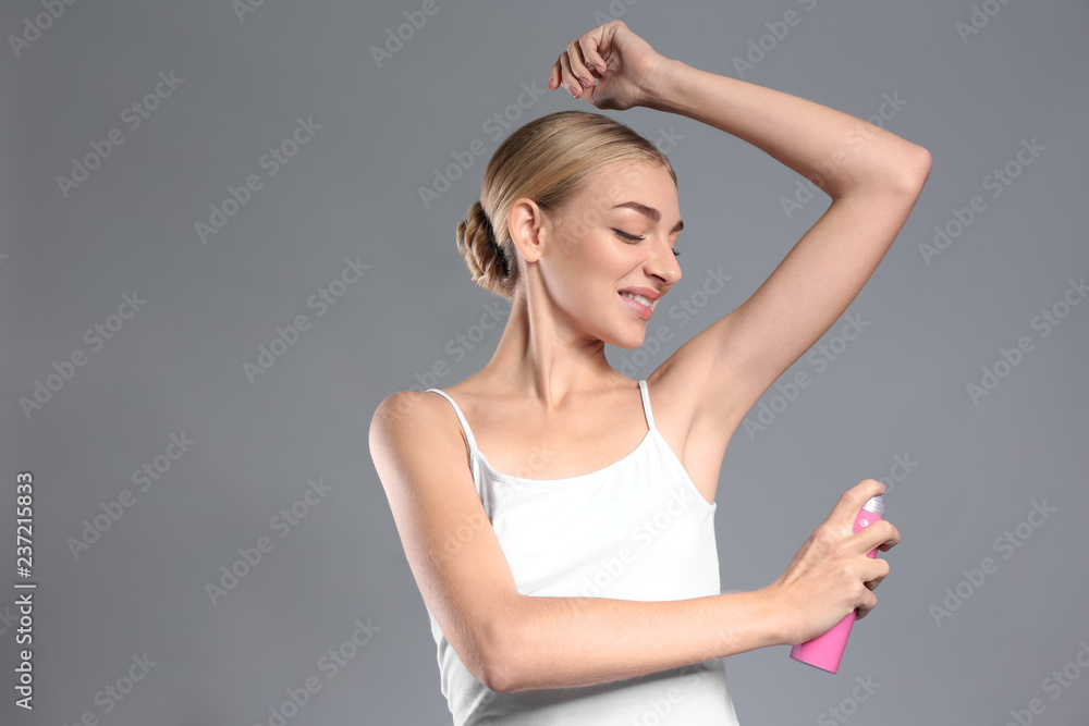 Beautiful young woman with deodorant on grey background Beautiful young woman with deodorant on grey background