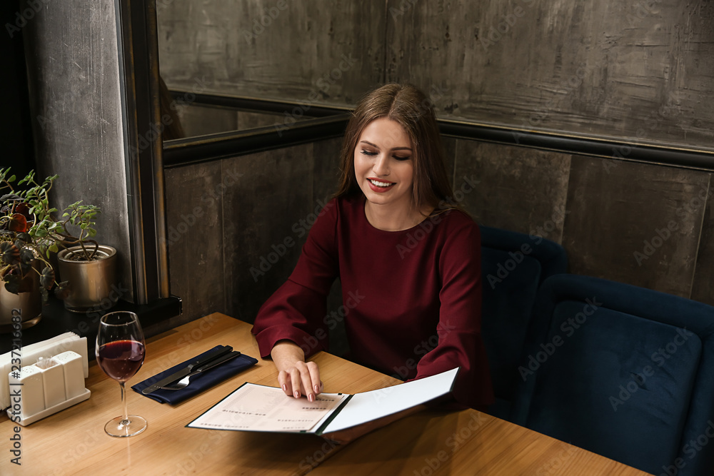 Naklejka premium Young woman looking through menu in restaurant