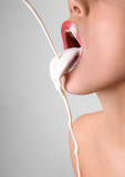 White liquid dripping into woman's mouth on light background. Erotic concept