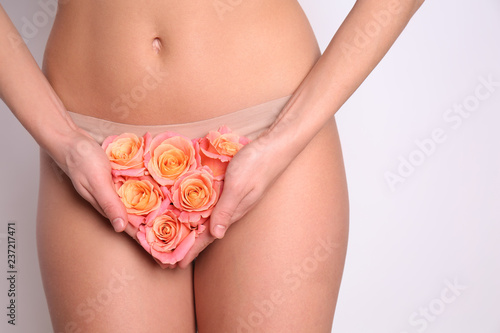 Sexy young woman holding roses near her panties, closeup. Erotic concept photo