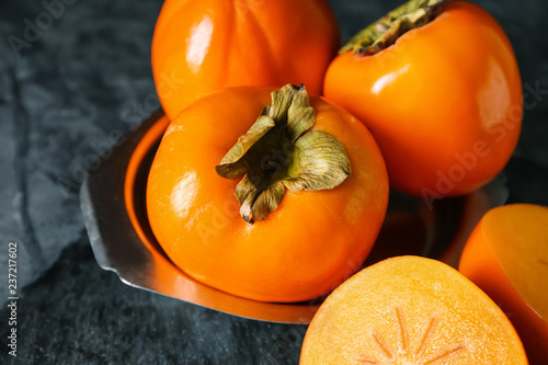 Plate with ripe persimmons on table, closeup