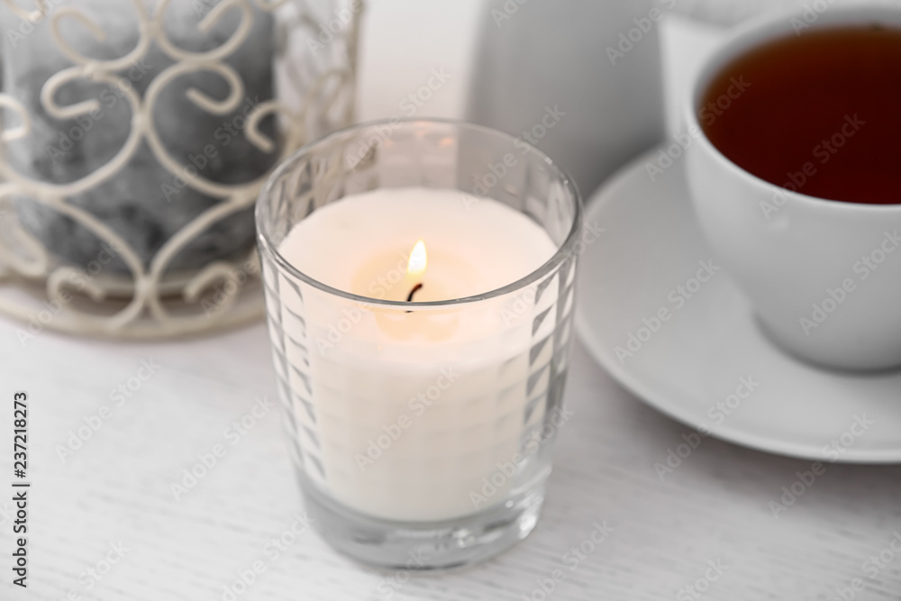 Burning candle and cup of tea on white wooden table Burning candle and cup of tea on white wooden table