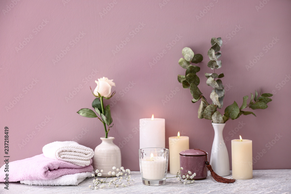 Beautiful composition with burning candles on table near color wall Beautiful composition with burning candles on table near color wall
