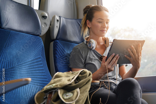 Young woman travelling by train with tablet and headphones photo