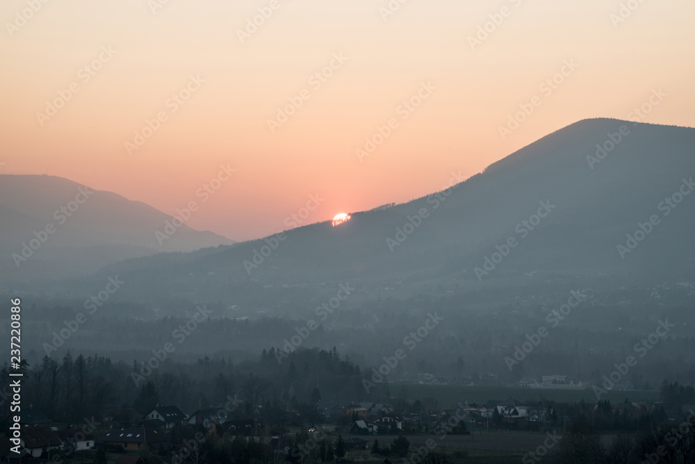 sunset over hill with colorful sky and village bellow