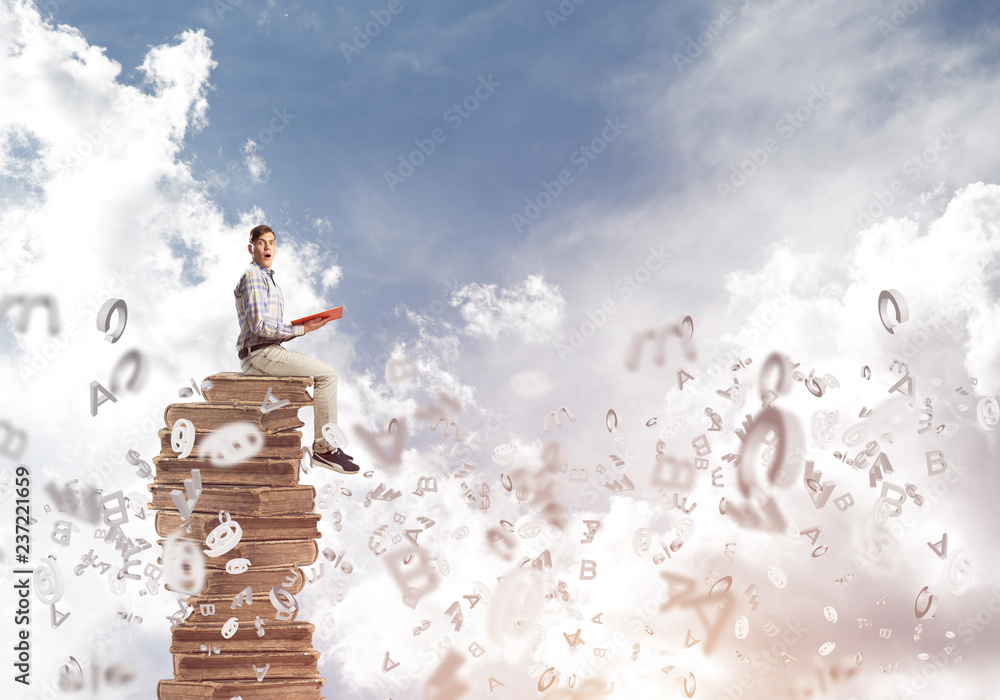 Man student on stack reading book and symbols flying around