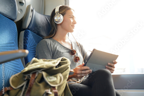 Young woman travelling by train with tablet and headphones photo