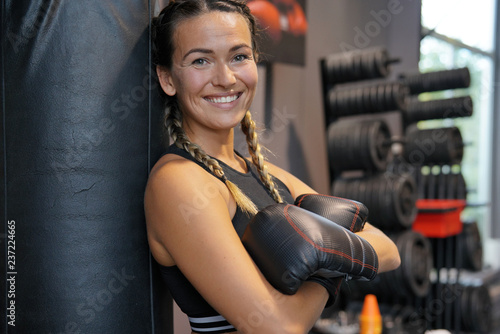 Woman wearing boxing gloves leaning on a punching bag