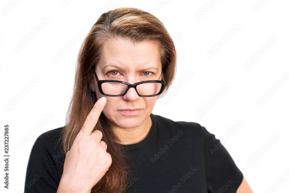 Beautiful but sad woman in glasses on a white background shows a finger on her ill with conjunctiva red eye