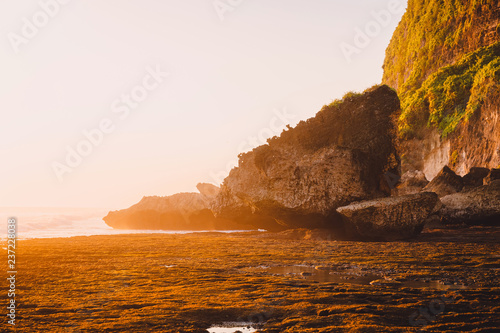 Rocky cliff with stones, ocean and sunset in Bali