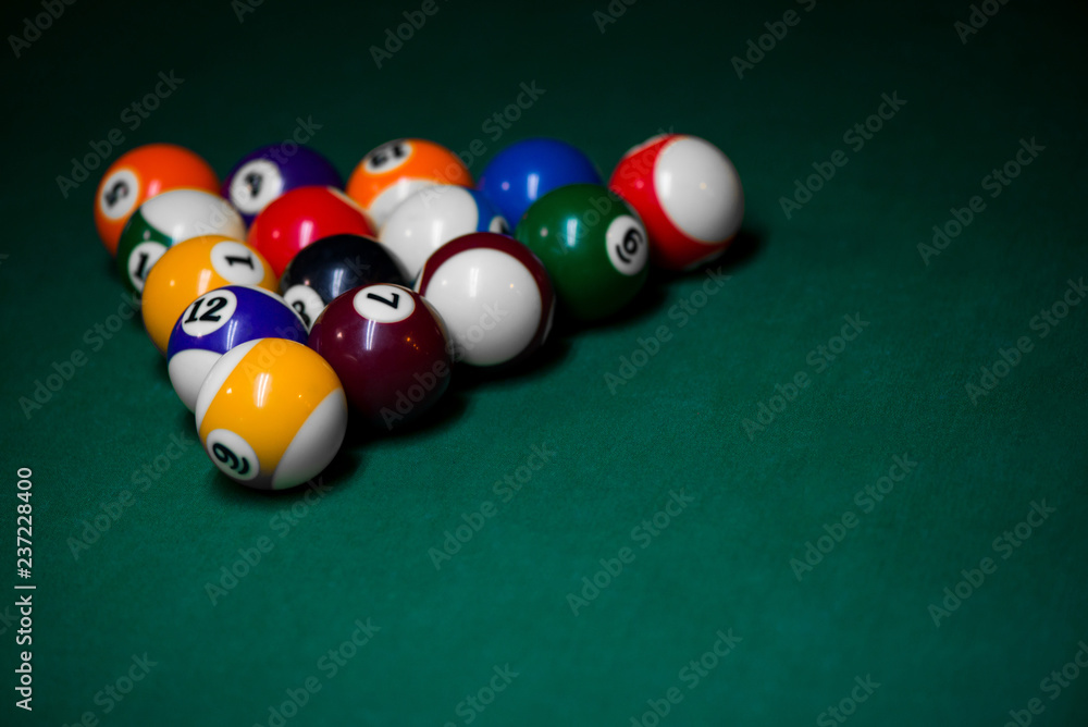 Sport billiard balls set arranged in shape of triangle on green billiard table in pub. Players are ready for the first hit of the round to start the billiard game. Sport billiard balls set arranged in shape of triangle on green billiard table in pub. Players are ready for the first hit of the round to start the billiard game.