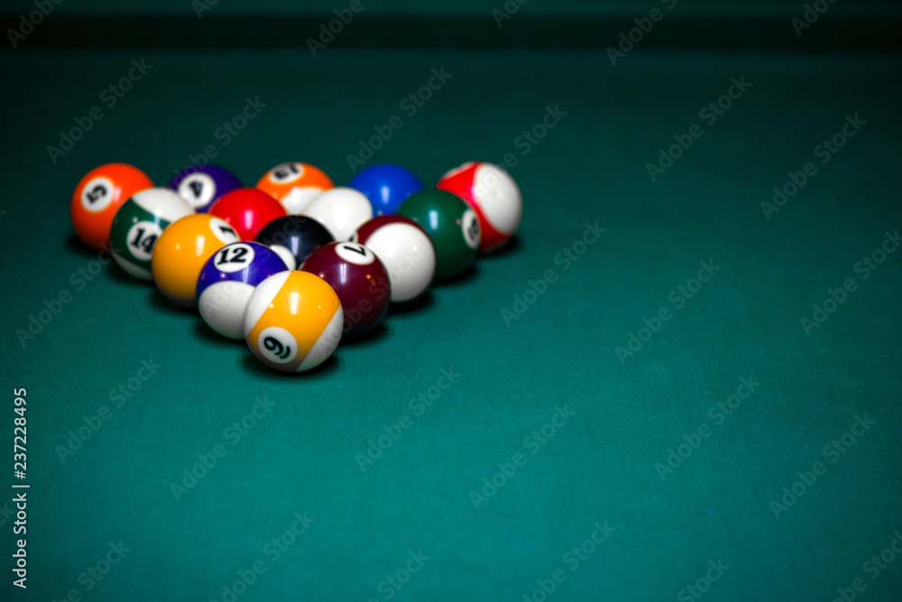 Sport billiard balls set arranged in shape of triangle on green billiard table in pub. Players are ready for the first hit of the round to start the billiard game. Sport billiard balls set arranged in shape of triangle on green billiard table in pub. Players are ready for the first hit of the round to start the billiard game.