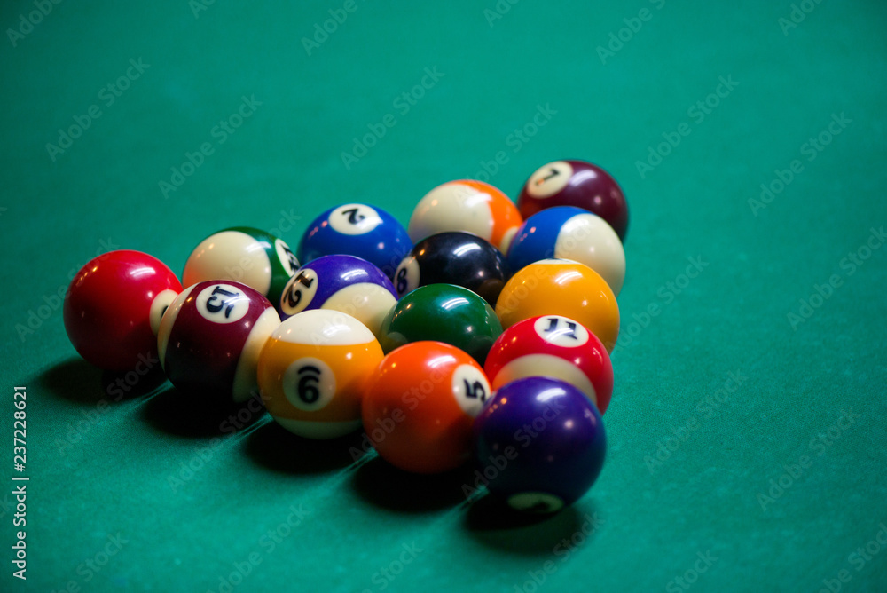 Sport billiard balls set arranged in shape of triangle on green billiard table in pub. Players are ready for the first hit of the round to start the billiard game. Sport billiard balls set arranged in shape of triangle on green billiard table in pub. Players are ready for the first hit of the round to start the billiard game.