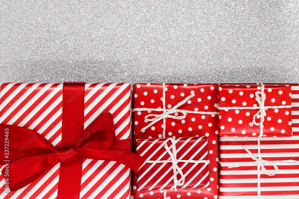 Obraz premium Various size wrapped in red paper with ornament Christmas gift boxes on shiny silver background