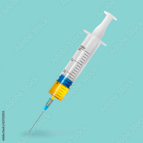 Syringe with yellow vaccine on green background. flu vaccination concept. medicine, health care