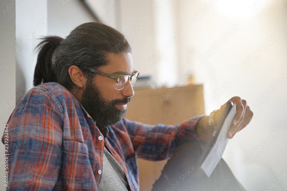 Hipster guy sitting on floor, connected with digital tablet