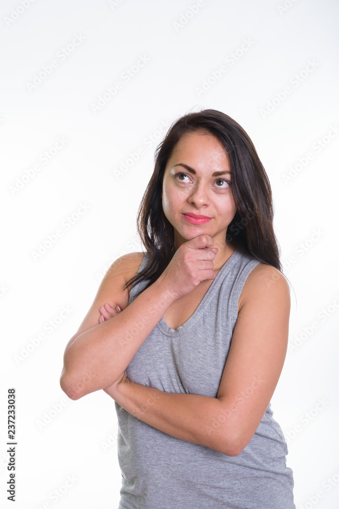 Studio shot of beautiful woman thinking with hand on chin agains Studio shot of beautiful woman thinking with hand on chin agains