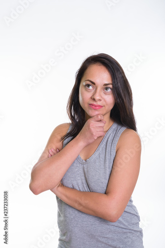 Studio shot of beautiful woman thinking with hand on chin agains © Ranta Images