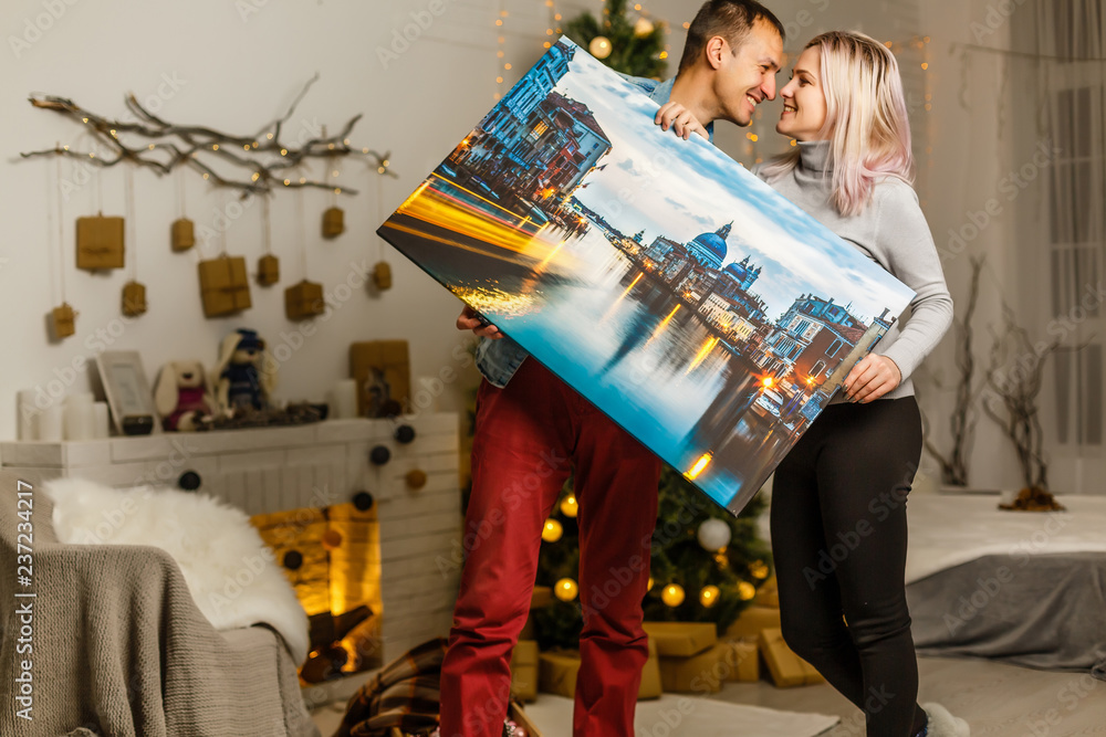 Happy young woman canvas and her boyfriend holding while moving into new home - obrazy, fototapety, plakaty 