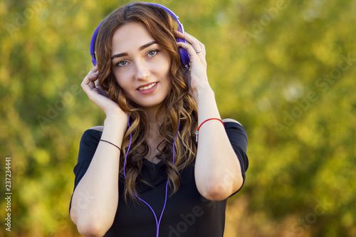portrait of a music lover teenager girl in headphones, young woman listening to lovely song on the nature in the field