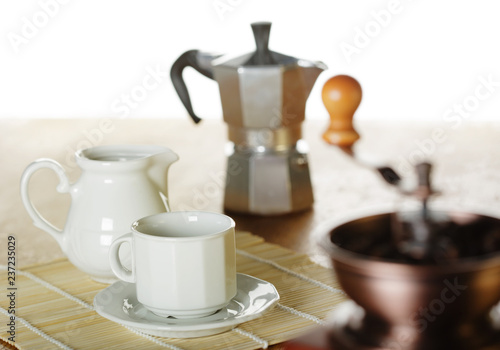 Making coffee. Coffee grinder, cup, light background