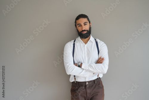 Hipster man with suspenders standing on background, isolated