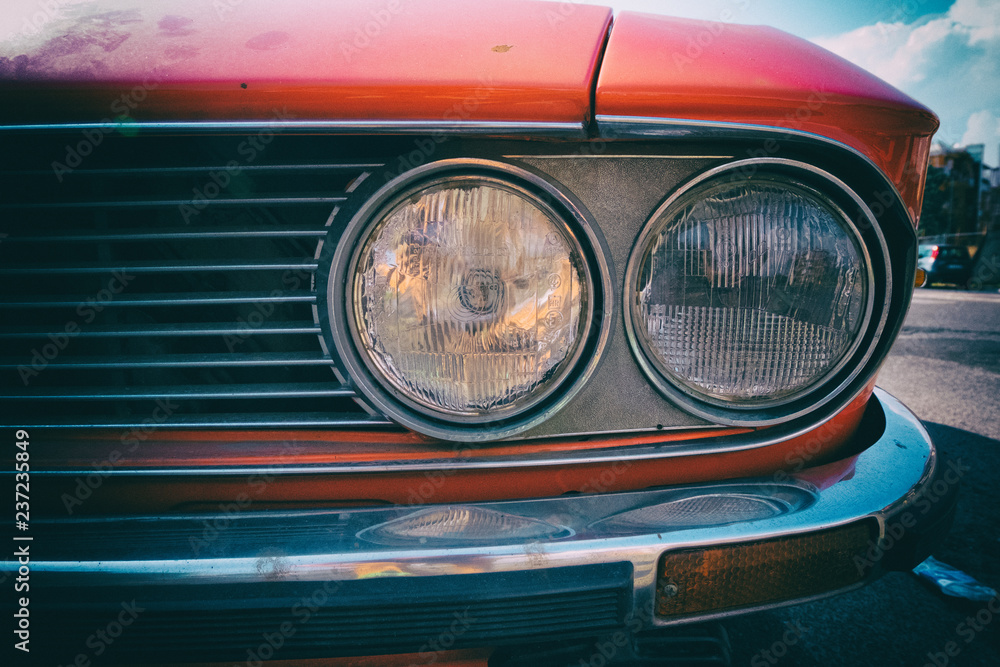 Close-up of headlight of a red vintage classic car.