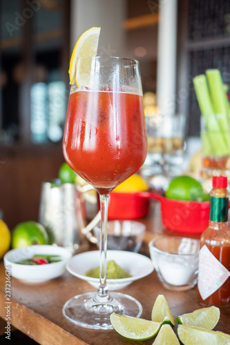 Delicious and classic Bloody Mary cocktail or tomato juice garnished with lemon wedge on a bar counter with ingredients background. Good for hangover. Bright and healthy theme. Natural light.