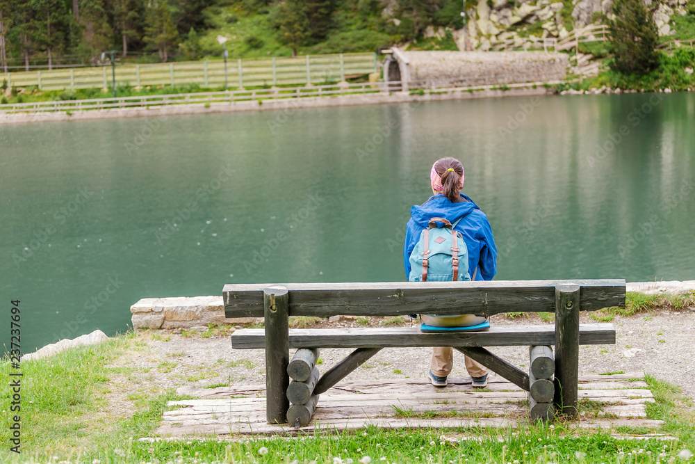 Woman sitting on a bench and enjoying the view at the beautiful alpine lake in Nuria valley, Spain Pyrenees Woman sitting on a bench and enjoying the view at the beautiful alpine lake in Nuria valley, Spain Pyrenees
