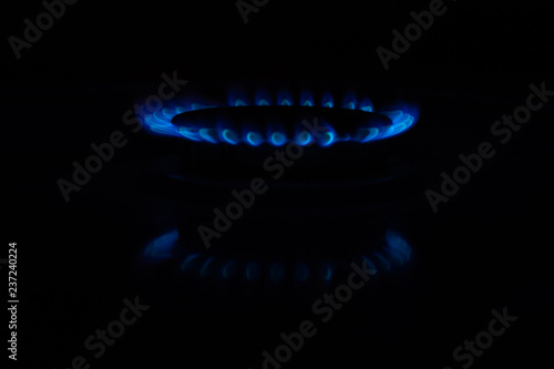 Circles of fire on a gas stove in the dark. Blue flame reflected on the surface