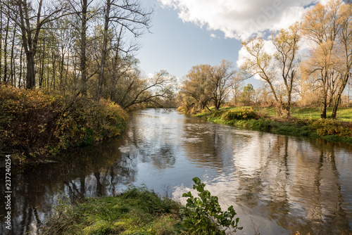 river tributary with colorful trees around during autumn day with blue sky and clouds photo