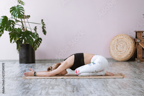 Beautiful girl in sportswear doing yoga Child's Resting Pose or Balasana on yoga mat photo