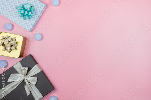 Festive christmas background. 3 colorful gift boxes with candles on a pink background with copy space on the right.
