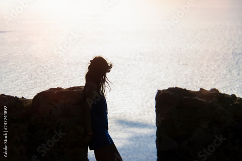 Silhouette of a girl on the background of the sea background and stone wall