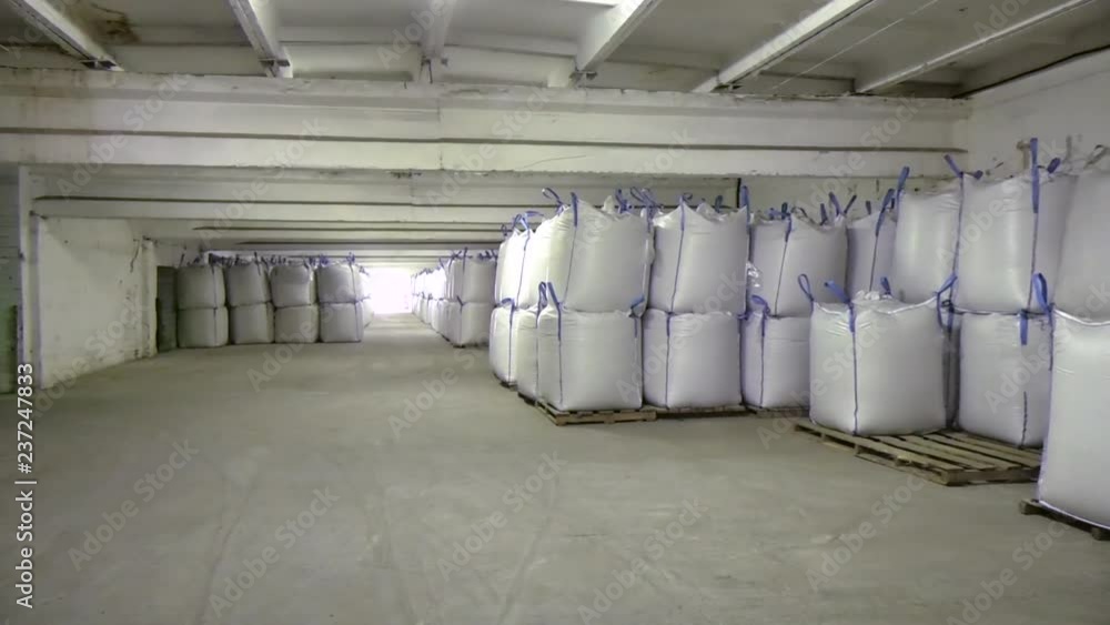 Hangar warehouse with big white polyethylene bags of industrial and logistics companies. Warehousing on the floor Hangar warehouse with big white polyethylene bags of industrial and logistics companies. Warehousing on the floor