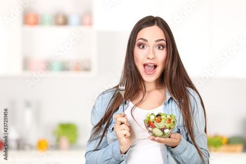 Beautiful woman eating fresh salad in the kitchen