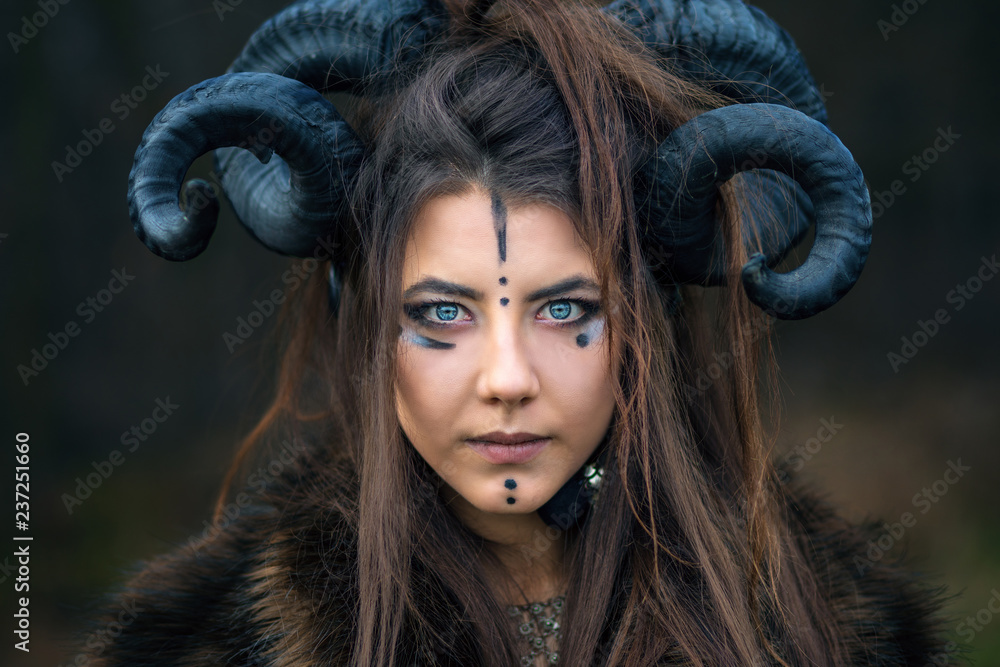 Outdoor portrait of beautiful scandinavian viking woman warrior with blue  eyes wearing ram horns looking at camera. Female hunter with specific makeup  wearing fur collar Stock Photo | Adobe Stock
