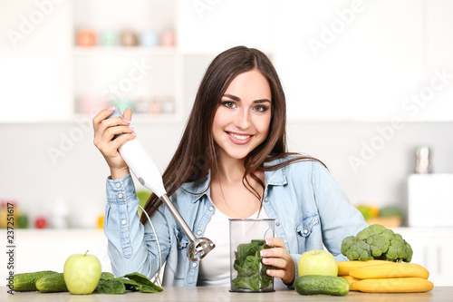 Beautiful woman making smoothie in the kitchen