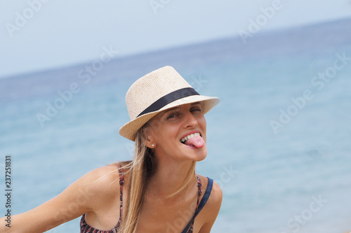 Beautiful girl shows tongue. blue sea background