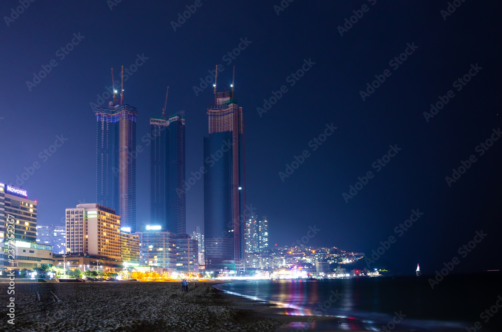 Fototapeta premium Office blocks at Huandae in Busan, South Korea seen from the beach at night.