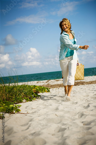 Mature adult woman running from the ocean at a beach.