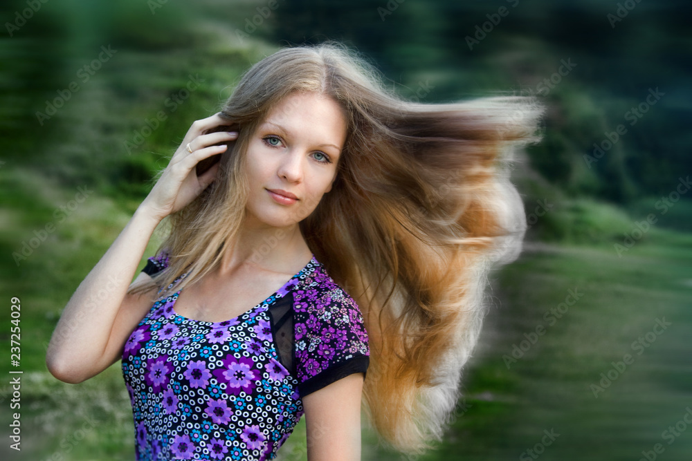 Naklejka premium Portrait of a beautiful girl with long hair in a meadow