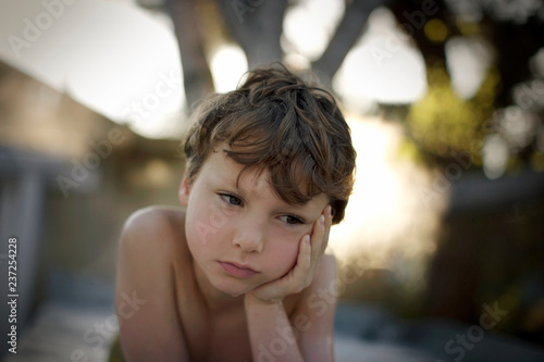 Serious young boy resting his face in his hand. photo