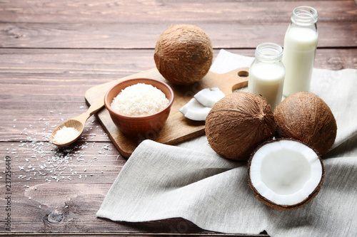 Coconut milk in bottles with flakes and napkin on wooden table