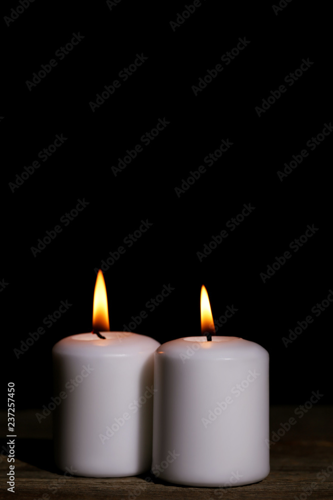 White burning candles on black background White burning candles on black background