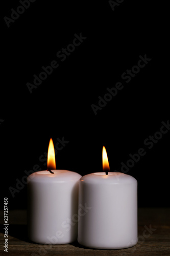 White burning candles on black background