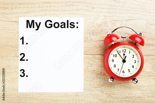 Inscription My goals with red alarm clock on wooden table