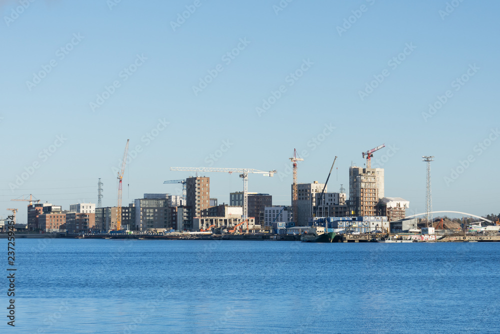 Large-scale construction with cranes on the bay coast of the city.