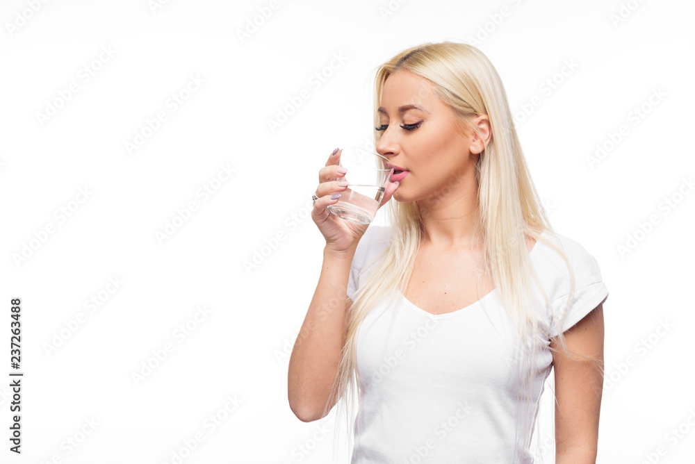 Obraz premium Healthy blond woman holding and drink glass of water on isolated white background