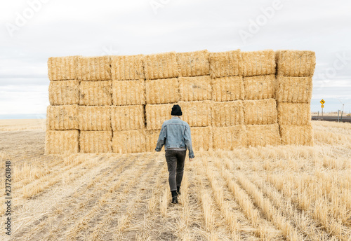 Lifestyle portrait of young adult female wearing denim coat in hay field after harvest photo